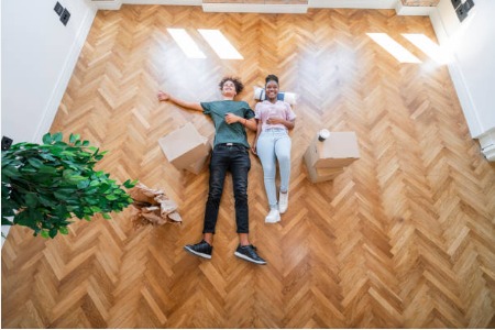 Happy couple relaxing in an open room with a few moving boxes and a houseplant